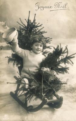 Beeldzijde kerstkaart, kindje op slede met sparren, 1910