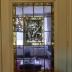 Rechthoekige glasramen gevat in 2 deuren met in het midden een afbeelding van Flor Coucke