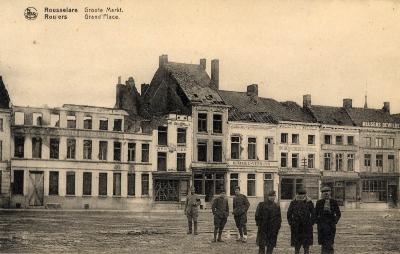 Enkele mannen en soldaten voor vernielde huizen op de Grote Markt