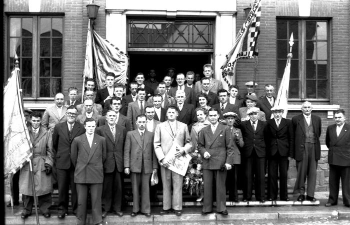 Kampioenviering vinkenzetters: groepsfoto aan gemeentehuis samen met burgemeester, Emelgem 18-08-1957