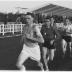 Fotoreportage atletiekwedstrijd: atleten lopen voorbij tribune, Izegem 1957