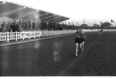 Fotoreportage atletiekwedstrijd: Herman en Leenaert lopen voorbij de tribune, Izegem 1957